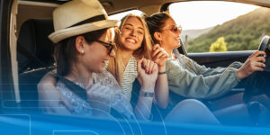 three teens are sitting in the seat of a car .