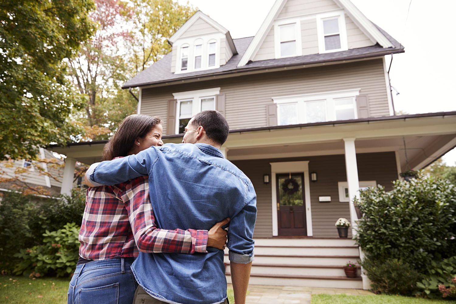 Homeowners embracing in front of their house